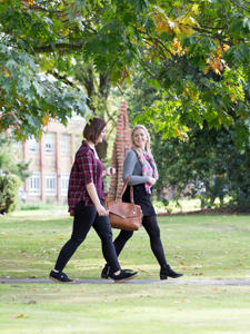 Two students are walking next to each other and smiling
